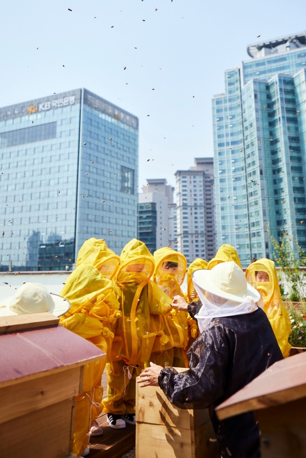 KB금융그룹 직원 가족들이 KB국민은행 본관 옥상에 설치된 'K-Bee' 도시 양봉장에서 벌 키우기 체험 활동을 하고 있다. (사진=KB금융그룹)